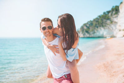 Portrait of couple piggybacking on beach