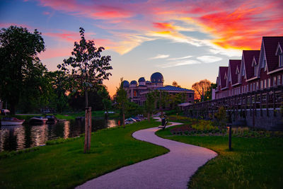 Footpath amidst buildings against sky during sunset