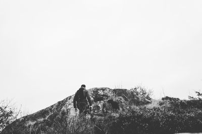 Low angle view of people standing on cliff against clear sky