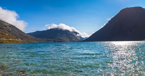 Scenic view of sea and mountains against blue sky