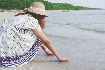 Side view of woman in hat at beach