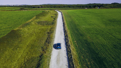 The car is moving on a sandy country road