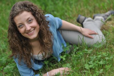 Portrait of smiling young woman lying on field