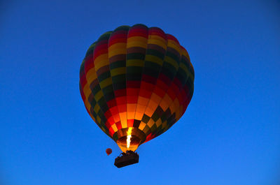 Low angle view of hot air balloon flying against clear blue sky