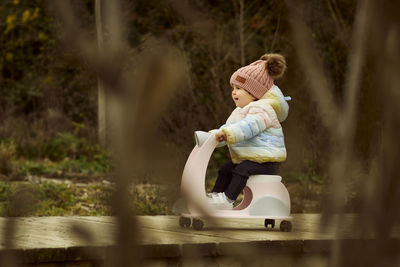 A 1 year old baby girl is with a pink motorcycle outside