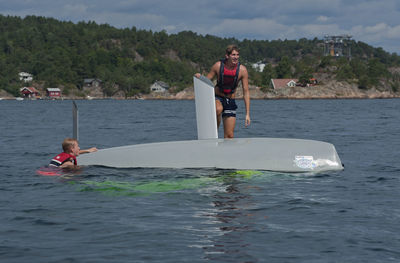 People on boat in sea against sky