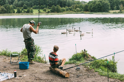 A young man teaches his children to fish during a family vacation at a camping site.