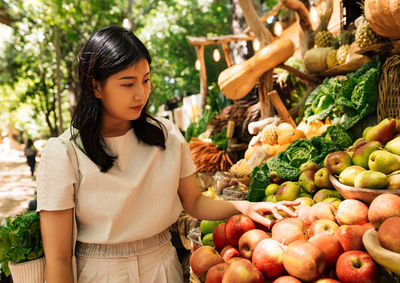 Portrait of young woman holding fruits at market stall