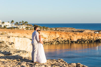 Rear view of woman on beach against clear sky