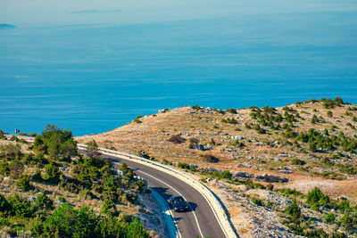 High angle view of road by sea against blue sky