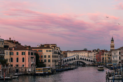 Grand canal passing through city buildings  and rialto bridge at sunset