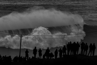 Silhouette people by sea against sky