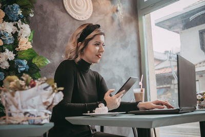 Young woman using phone while sitting on table