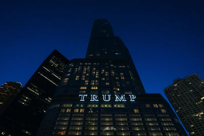 Low angle view of illuminated buildings against clear blue sky at night