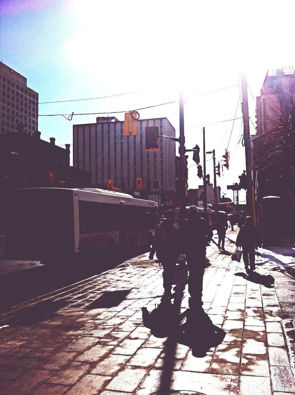 building exterior, architecture, built structure, city, sunlight, men, city life, street, silhouette, walking, sky, full length, shadow, lifestyles, sidewalk, leisure activity, building, person, outdoors