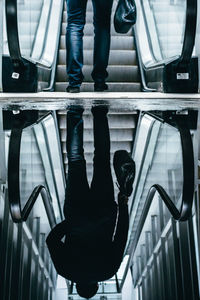 Reflection of man on puddle by escalator