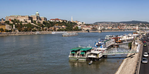 Boats on danube river at harbor against sky in city during sunny day