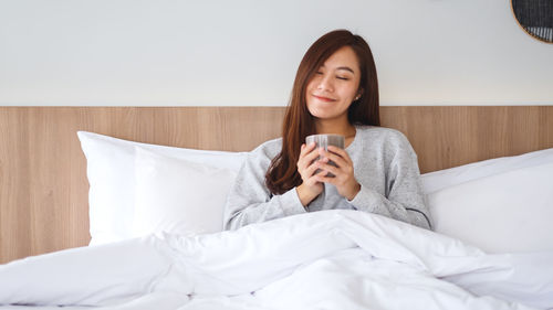 Young woman sitting on bed at home