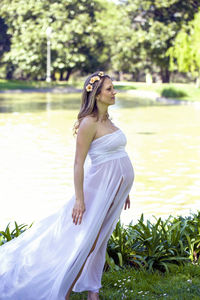 Pregnant woman standing against pond at park