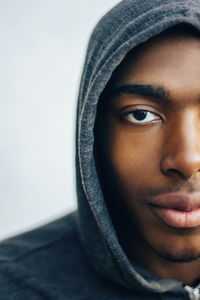 Close-up portrait of confident sportsman in hooded shirt sitting against wall