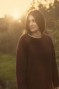 Portrait of beautiful young woman standing against trees