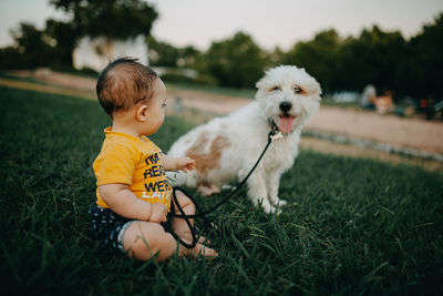 Full length of a child and dog on field