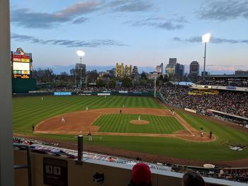 Group of people on soccer field by cityscape against sky