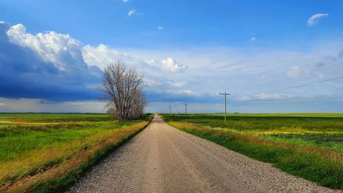 Road amidst field against sky