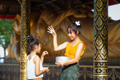 Side view of young woman standing against building