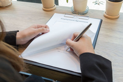 Cropped image of businesswoman signing employment contract at desk