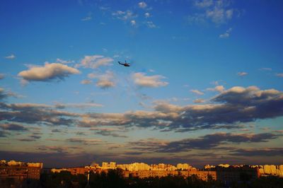 Airplane flying over cityscape against sky