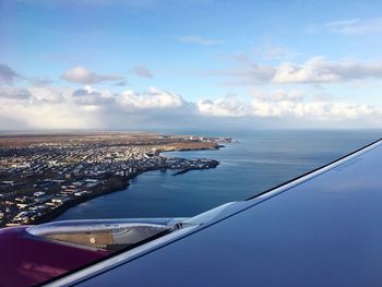 Aerial view of city by sea against sky