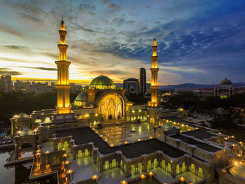 Illuminated federal territory mosque against sky during sunset