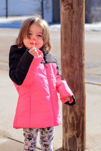 Portrait of girl holding lollipop on footpath