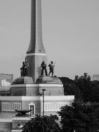 Sculpture in city against sky