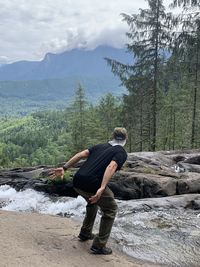 Full length of man standing at riverbank in forest