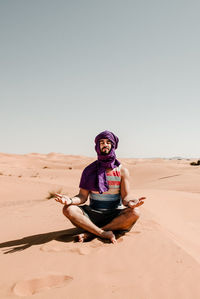 A man in a turban meditating on a dune in the sahara desert