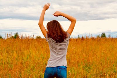 Young woman standing on field against sky