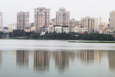 Reflection of buildings in lake against clear sky