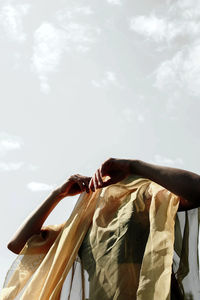 Low angle view of woman hand against sky