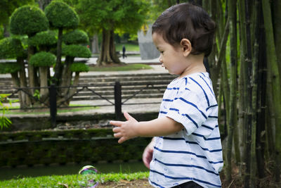 Side view of boy standing against plants