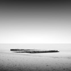 Pier at beach against sky during foggy weather