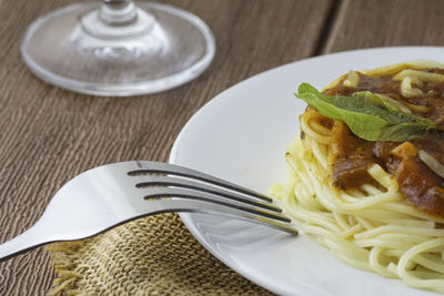 Spaghetti in a white plate on a wooden table 