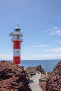 Lighthouse by sea against sky