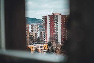 Buildings against sky seen through glass window