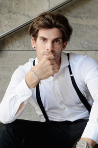 Portrait of man wearing suspenders while sitting on steps