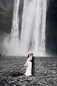 Woman standing against waterfall