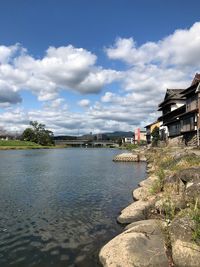 Scenic view of river by buildings against sky