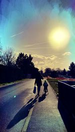 Rear view of people walking on road against sky