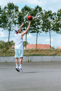 Full length of man playing with basketball